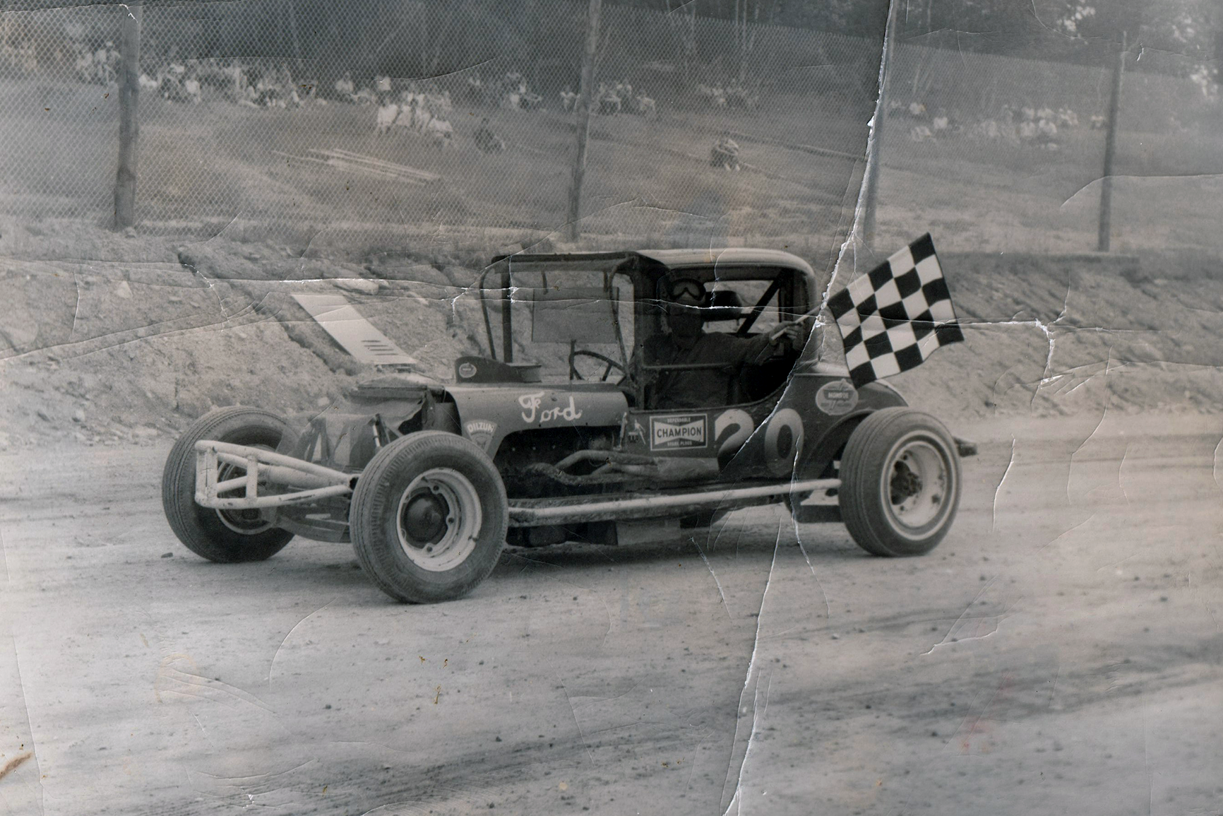 Jim Nichols driving his racecar holding the checkered flag after a victory.