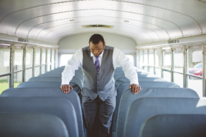 Best man at a wedding thinking in a school bus.