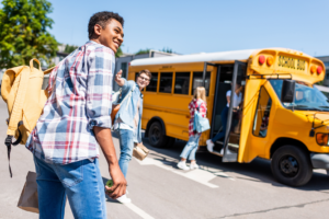 Young adults getting on a school bus.